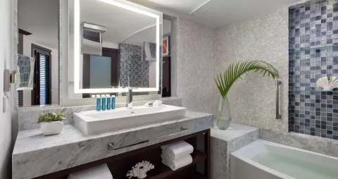 Guest bathroom with marble vanity, lit mirror and bathtub at Sandals Grenada.