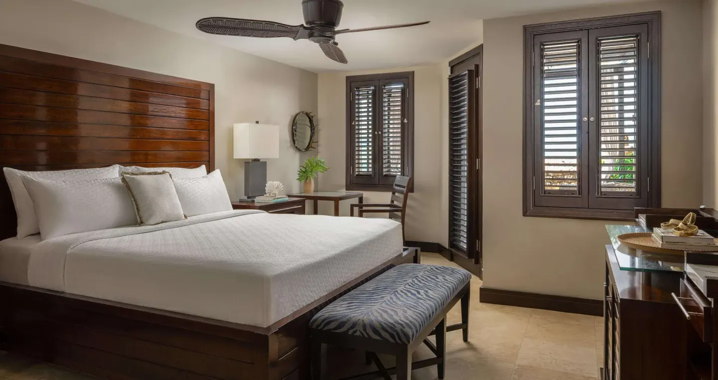 King bed, zebra-print bench and shuttered windows in a guest room at Sandals Grenada.