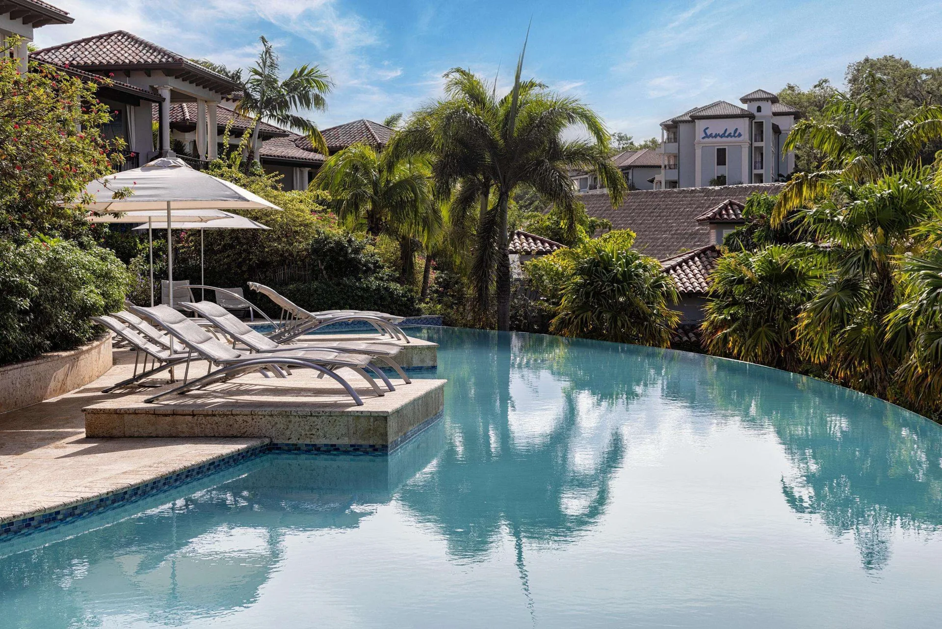 Infinity pool with lounge chairs and palms at Sandals Grenada.