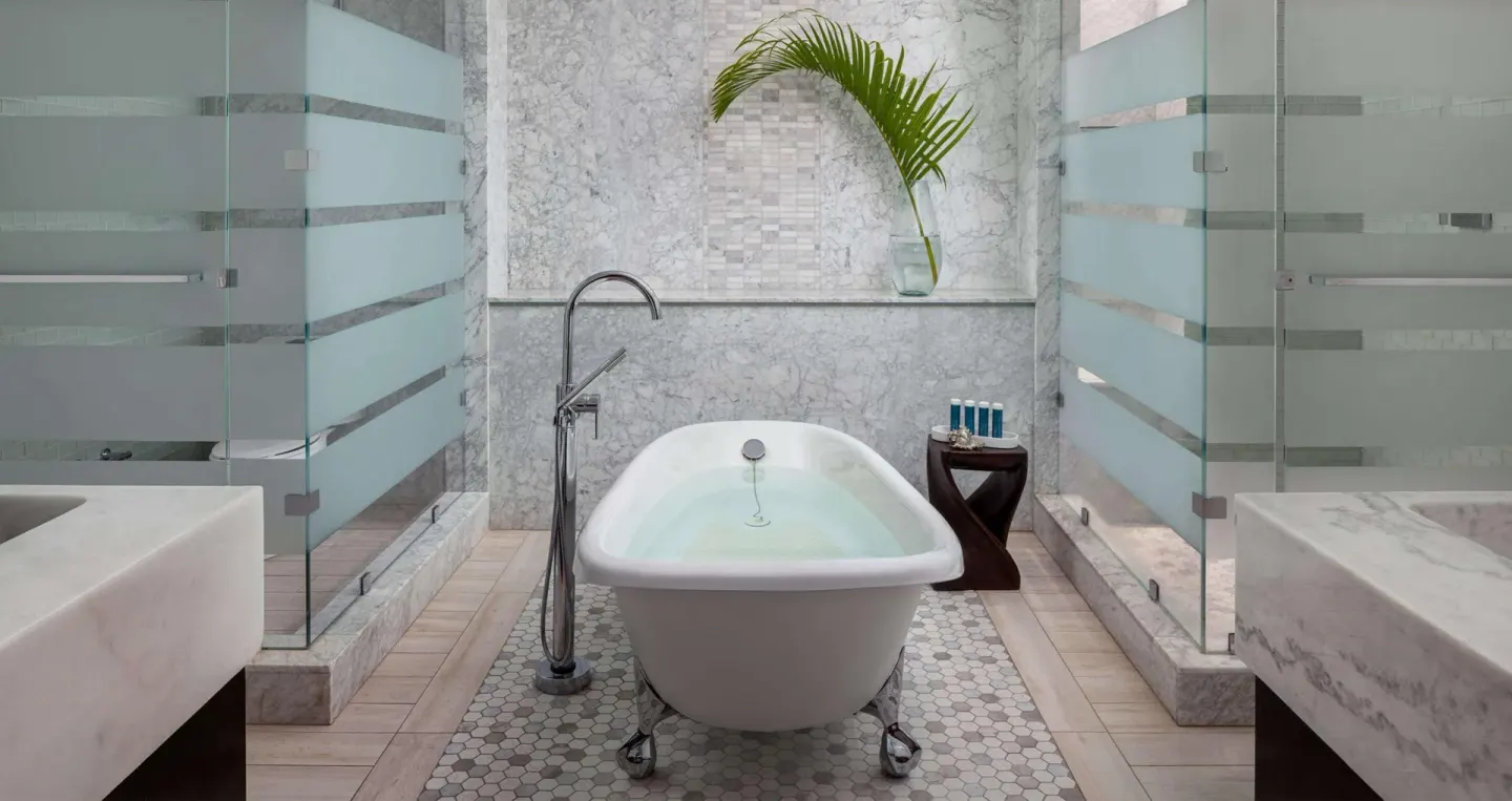 Freestanding bathtub between glass showers in a bathroom at Sandals Grenada.