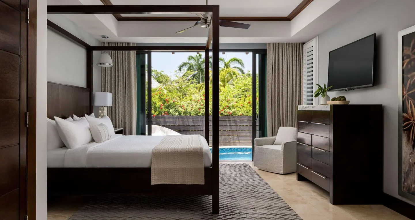 Four-poster king bed and poolside terrace in a guest room at Sandals Grenada.