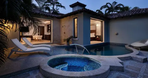Private pool courtyard with spa, loungers, and lit suite interiors at Sandals Grenada.