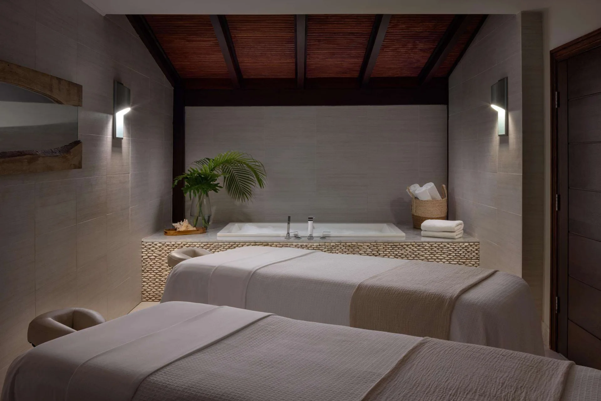 Spa treatment room with two massage beds and a soaking tub at Sandals Grenada.
