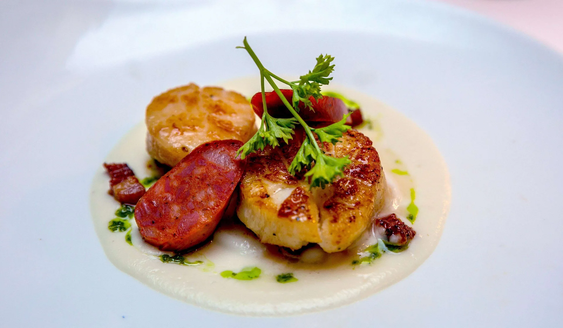 Plated seared seafood dish with sausage, sauce, and herbs at Sandals Grenada.