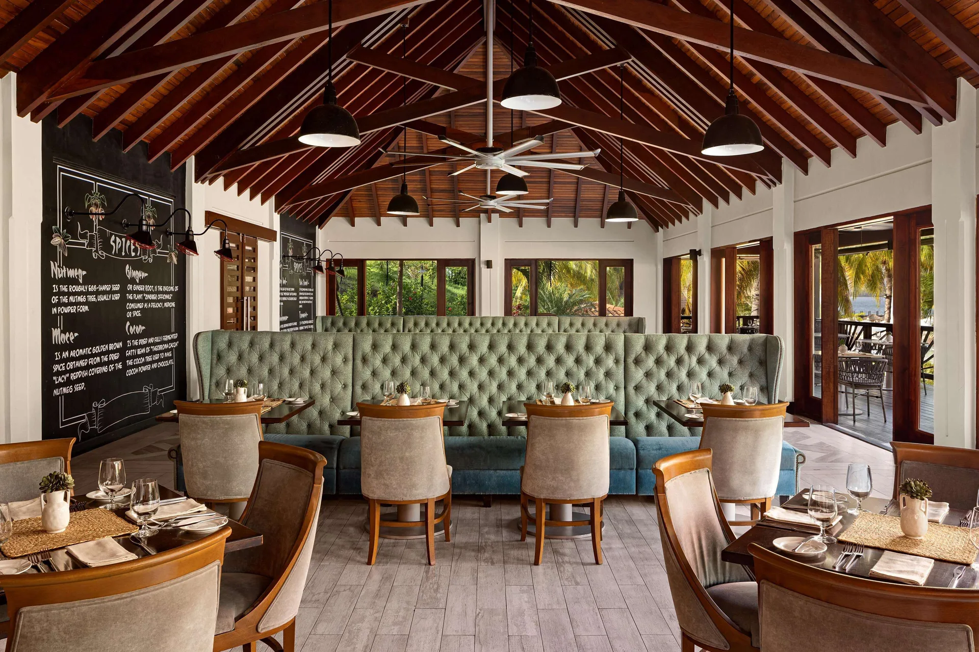 Spices dining room with tufted banquettes and chalkboard-style wall menus at Sandals Grenada.