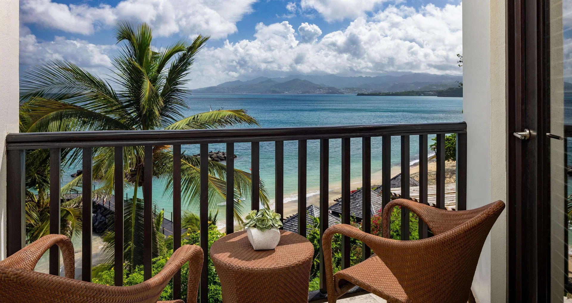Balcony seating overlooks Pink Gin Beachfront Club Level Room views at Sandals Grenada.