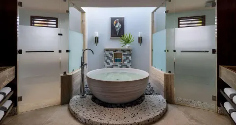 Round soaking tub between glass showers in a suite bathroom at Sandals Grenada.