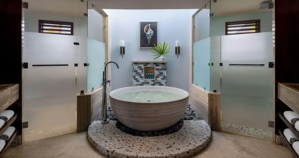 Round soaking tub between glass showers in a suite bathroom at Sandals Grenada.