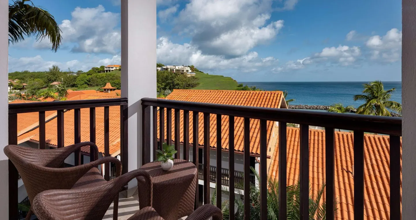 Balcony seating with ocean and terracotta roof views from a room at Sandals Grenada.