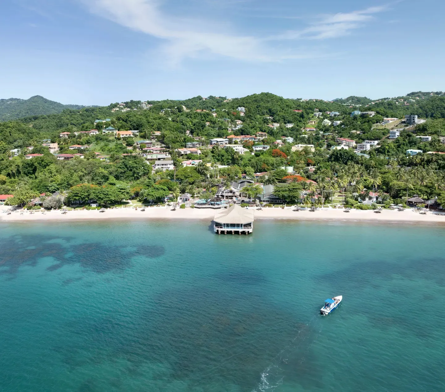 Aerial view of Sandals Halcyon beachfront, pier, and turquoise water.