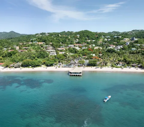 Aerial view of Sandals Halcyon beachfront, pier, and turquoise water.