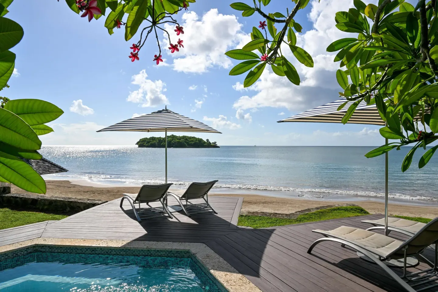 Beachfront pool deck with loungers, umbrellas, and ocean view at Sandals Halcyon.