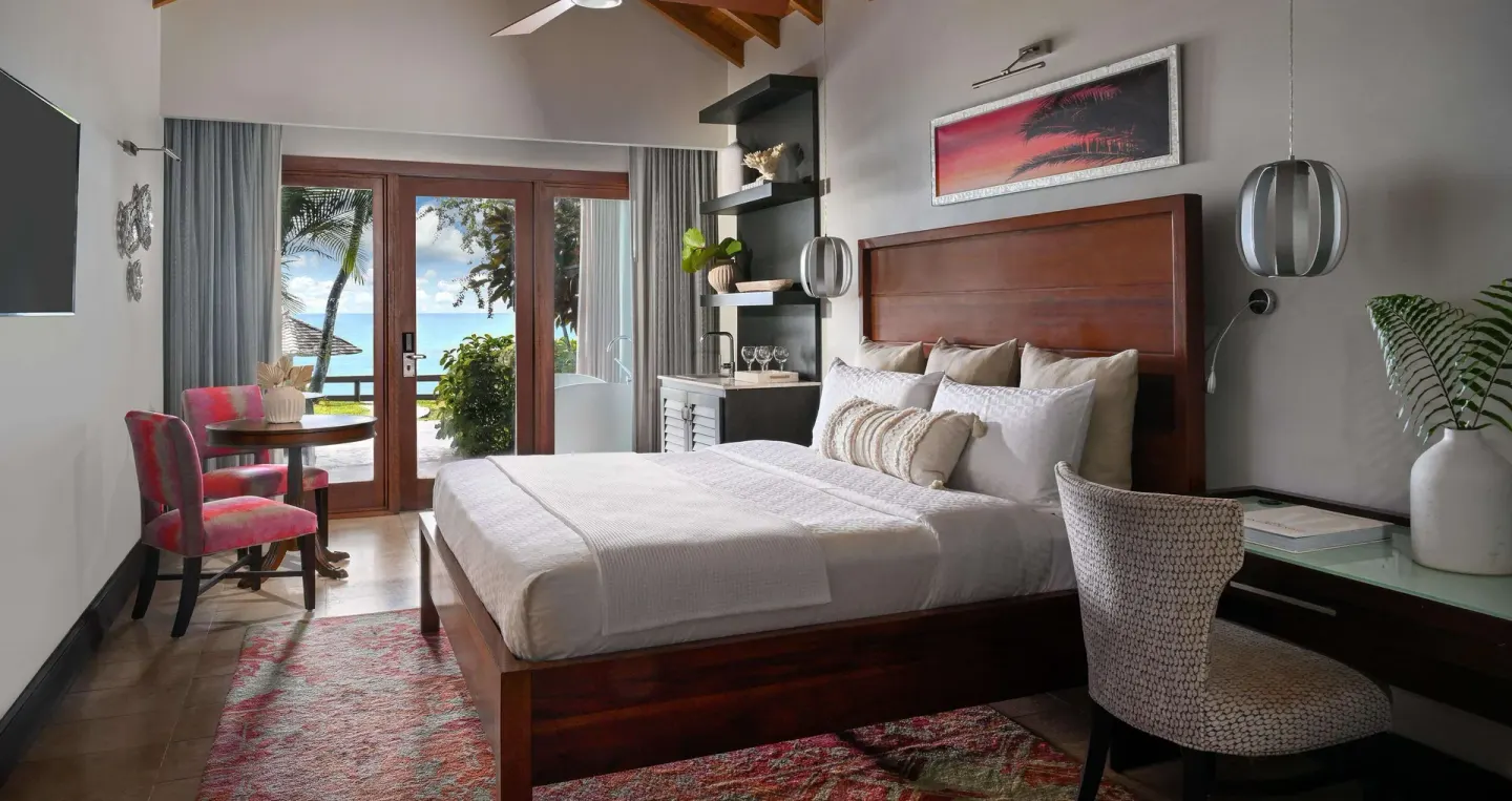 King bed room with desk, sitting area, and ocean-facing doors at Sandals Halcyon.