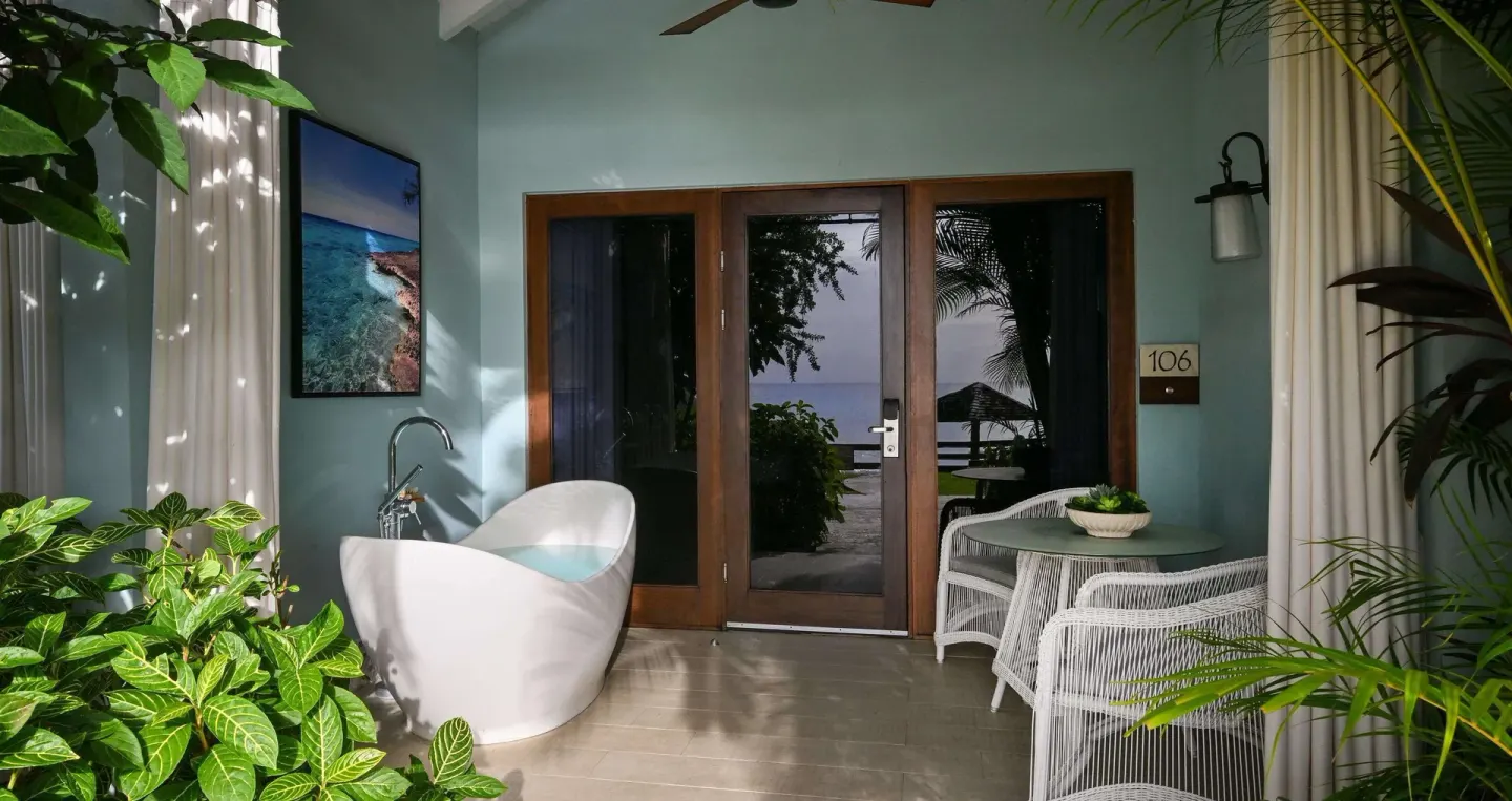 Covered guest room patio with soaking tub and sea-facing doors at Sandals Halcyon.
