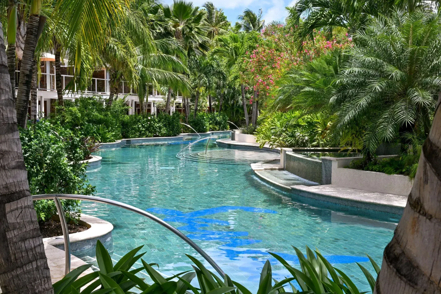 Tropical lagoon pool with palms and resort buildings at Sandals Halcyon.