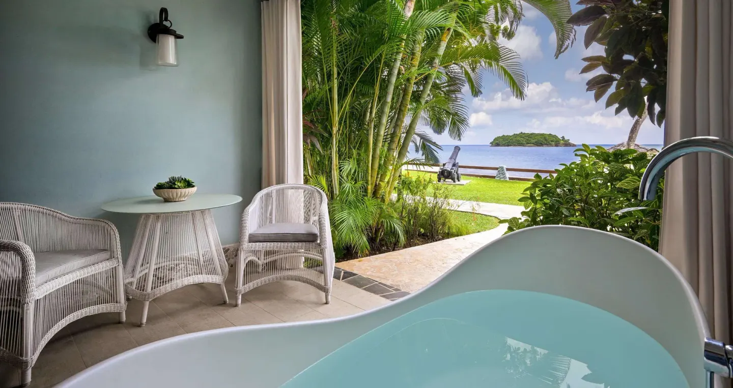 Outdoor soaking tub and patio seating with ocean view at Sandals Halcyon.