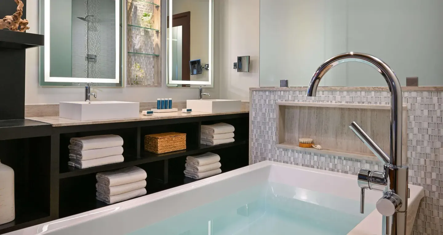 Bathroom with soaking tub, double sinks, towels, and glass shower at Sandals Halcyon.