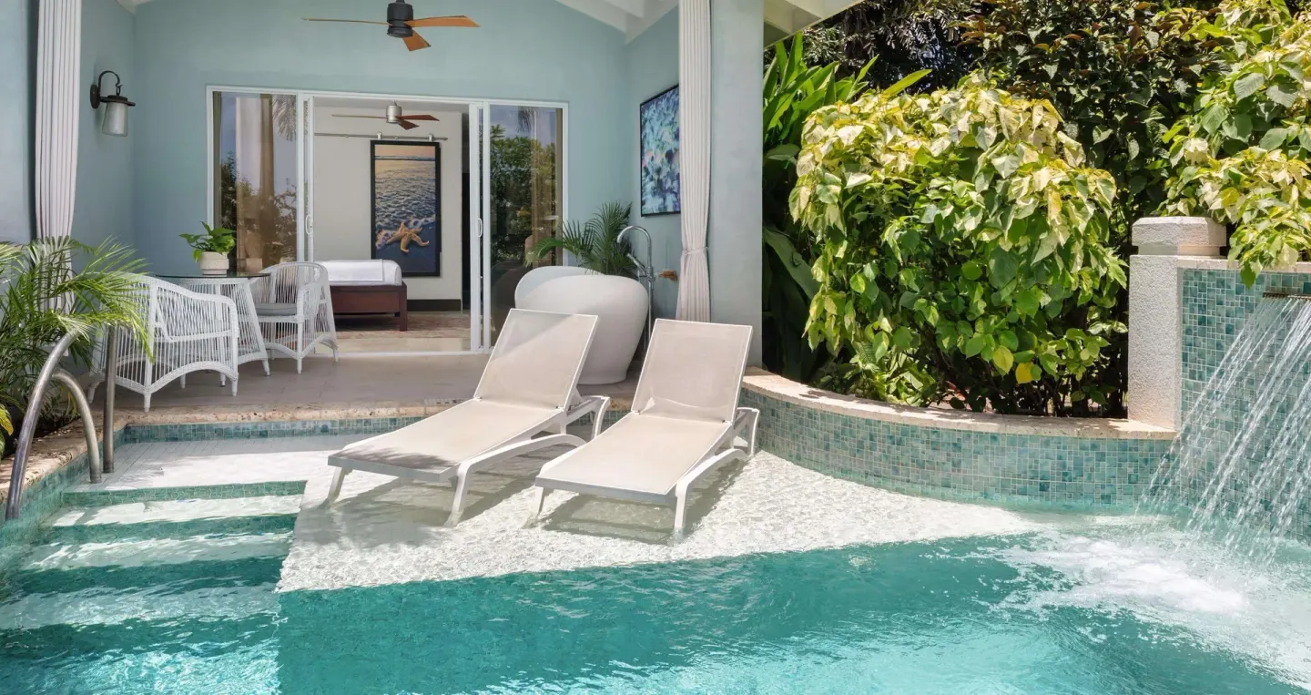 Swim-up patio with loungers, pool, and bedroom entrance at Sandals Halcyon.