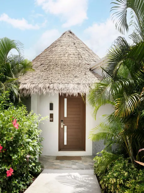 Thatched guest room entrance surrounded by tropical plants at Sandals Halcyon.