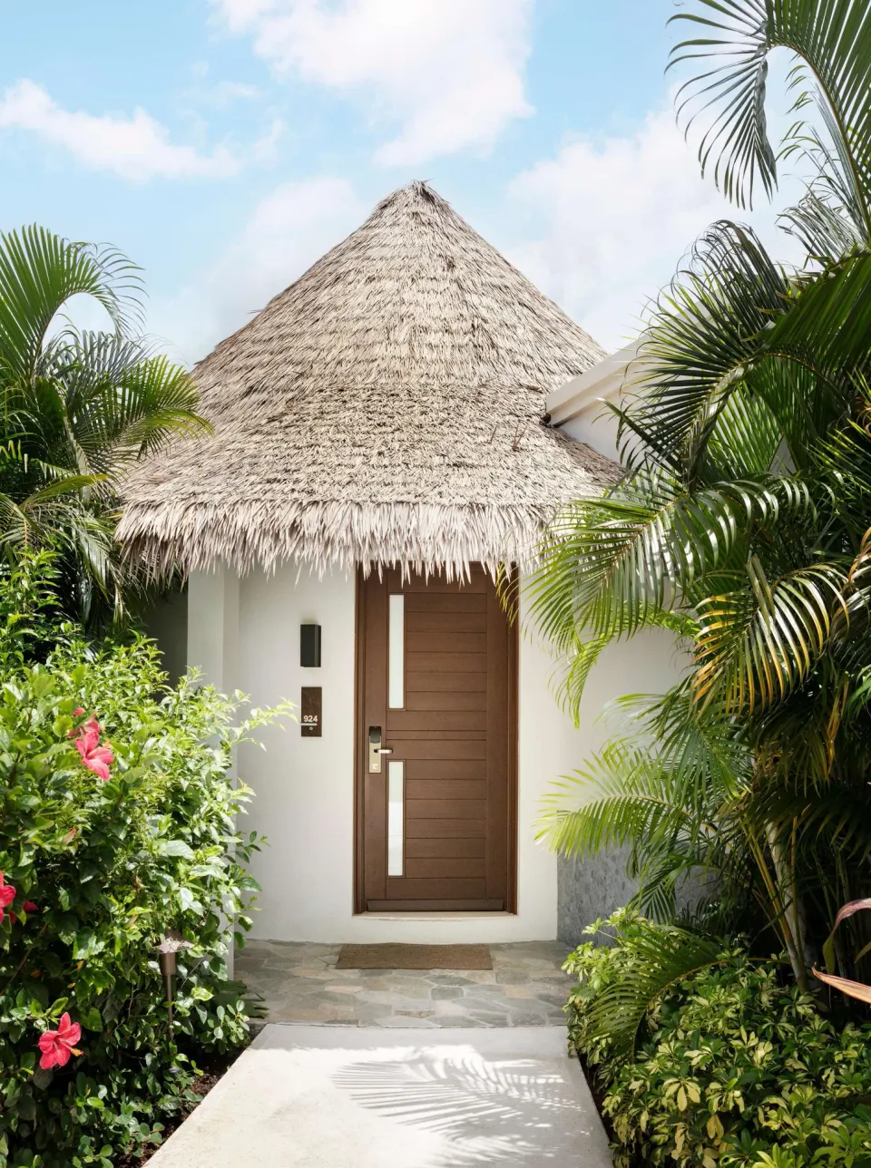 Thatched guest room entrance surrounded by tropical plants at Sandals Halcyon.