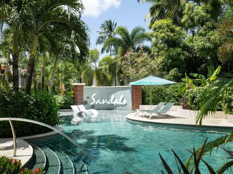Tropical pool with in-water loungers and a Sandals wall sign at Sandals Halcyon.