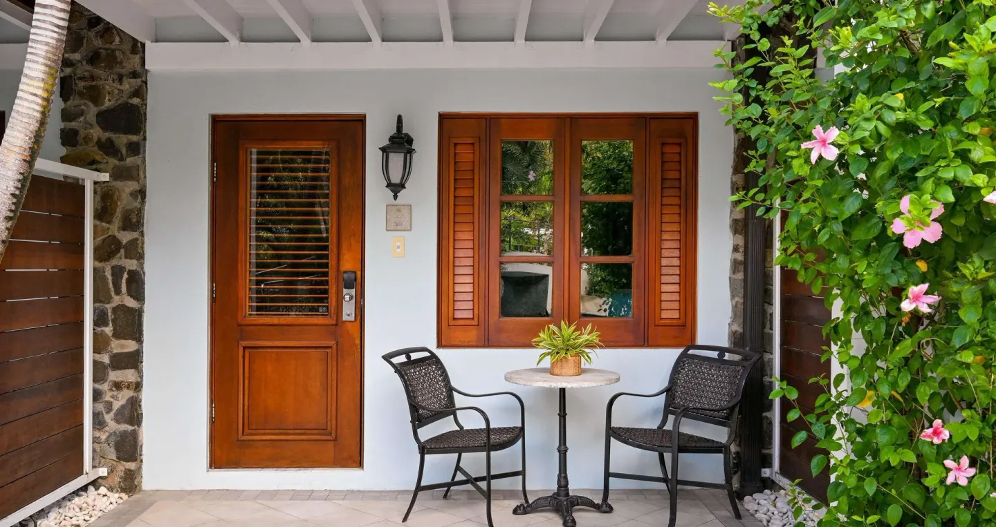 Club Room exterior entry with patio table and garden plants at Sandals Halcyon.