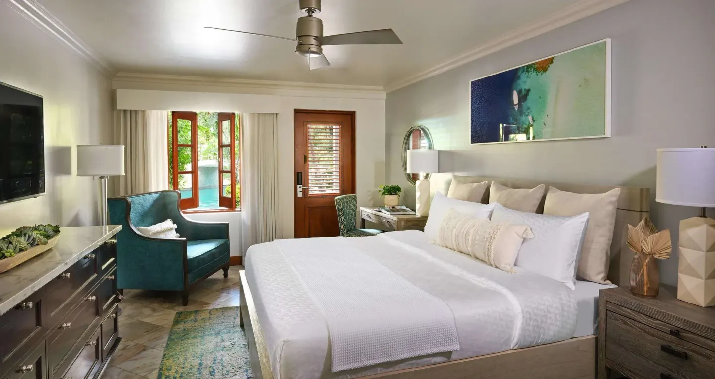 Club Room king bed with teal chair and swim-up view at Sandals Halcyon.