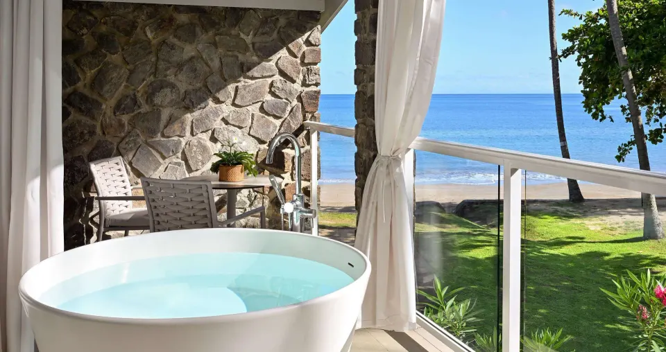 Ocean-view balcony with soaking tub and seating outside a Club Room at Sandals Halcyon.