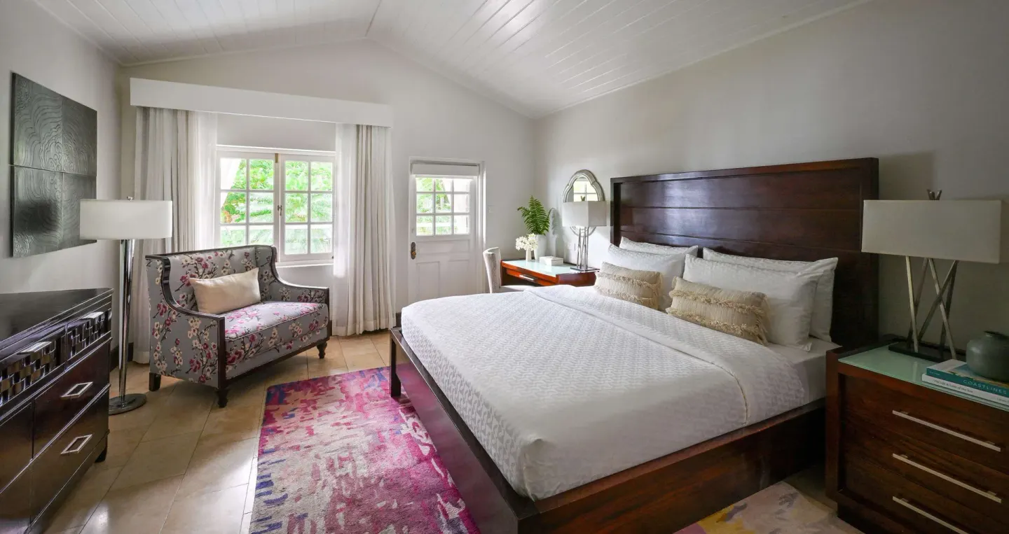 Club Room bedroom with king bed, floral loveseat, and bright windows at Sandals Halcyon.