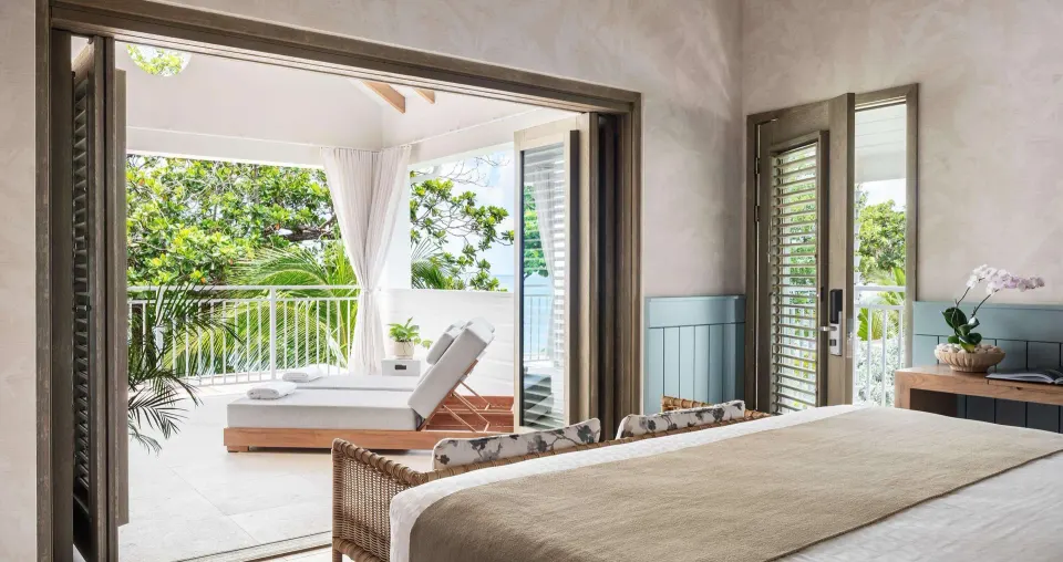 King bed facing a balcony lounge in a Shore House Butler Suite at Sandals Halcyon.