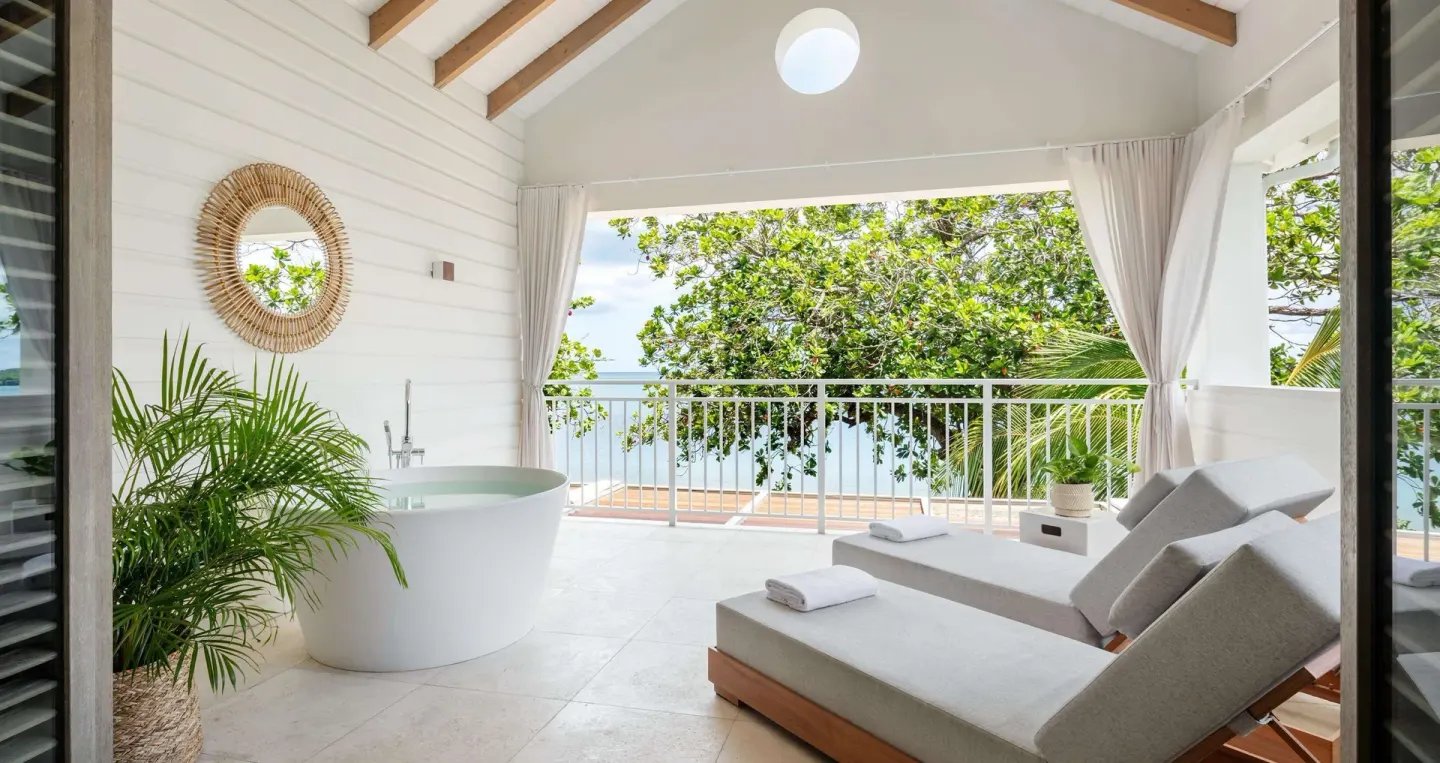 Ocean-view balcony with soaking tub and loungers in a Shore House Butler Suite at Sandals Halcyon.