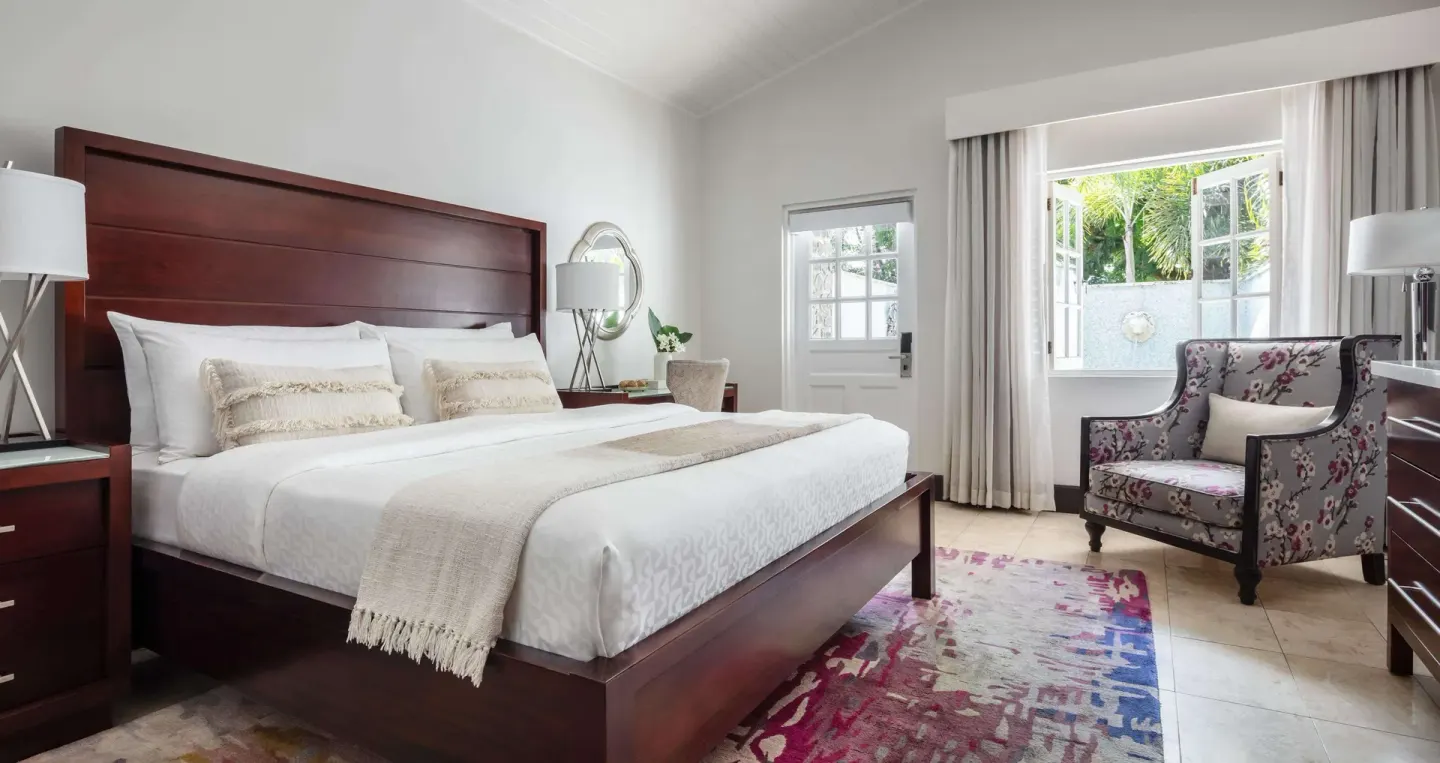 Honeymoon pool view room with king bed and floral chair at Sandals Halcyon.