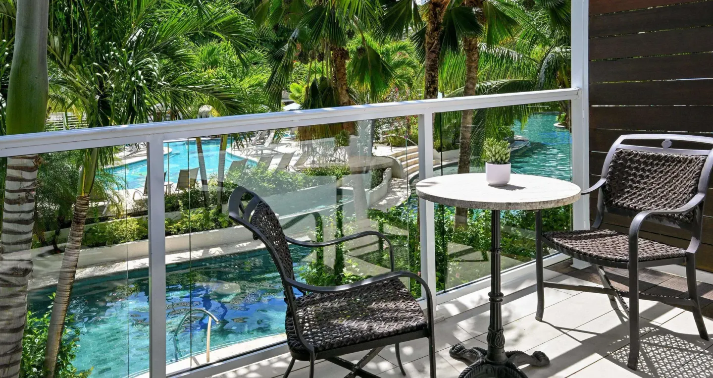 Balcony seating overlooking lagoon pool and palms at Sandals Halcyon.