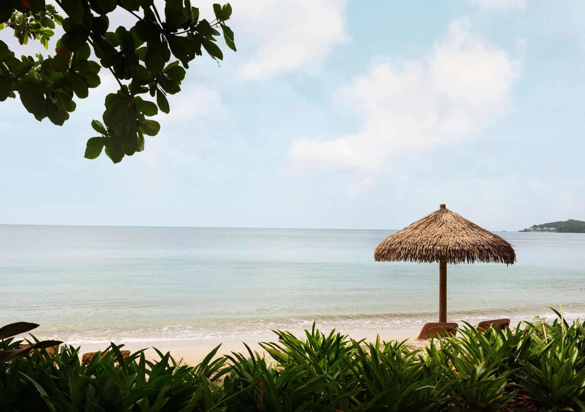Quiet beach scene with palapa shade and calm water at Sandals Halcyon.