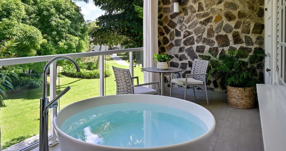 Garden-view balcony with soaking tub and seating at Sandals Halcyon.