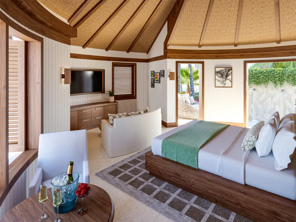 Guest room with king bed, vaulted ceiling, seating area, and outdoor shower at Sandals Halcyon.