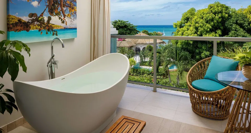 Balcony soaking tub with ocean and garden views at Sandals Montego Bay.
