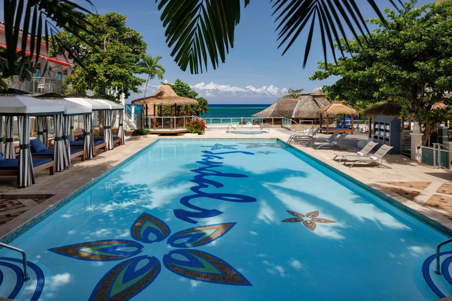 Beachfront pool with cabanas, loungers, and ocean beyond at Sandals Montego Bay.