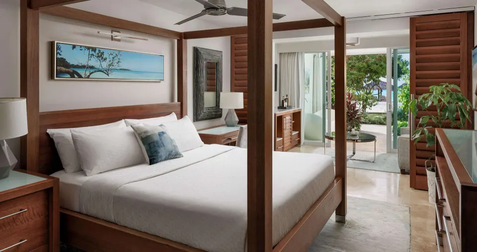 Four-poster king bed guest room with patio doors at Sandals Montego Bay.