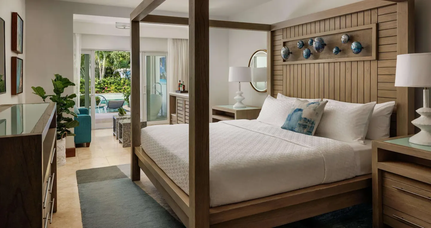Four-poster king bedroom with sitting area and patio view at Sandals Montego Bay.