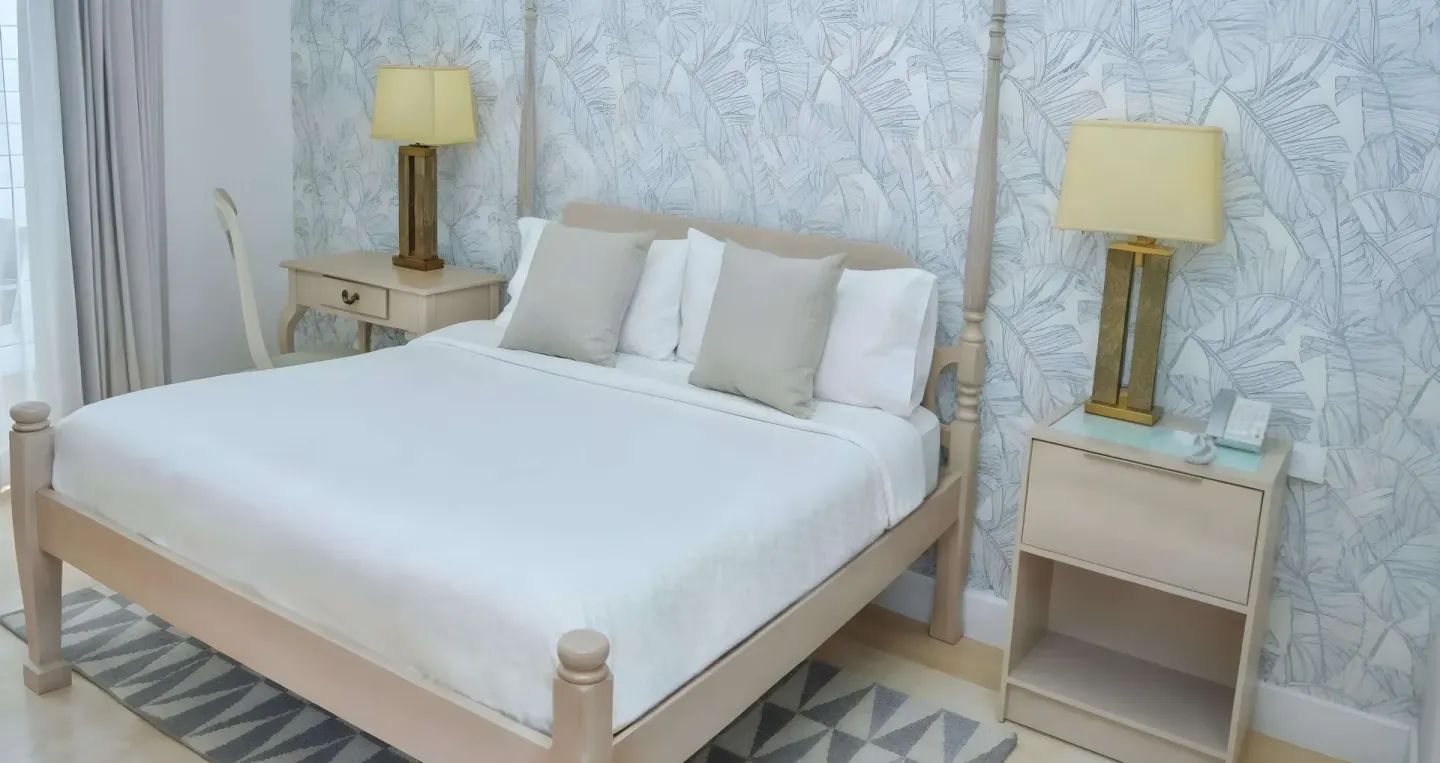 King bed with pale wood nightstands in a guest room at Sandals Montego Bay.