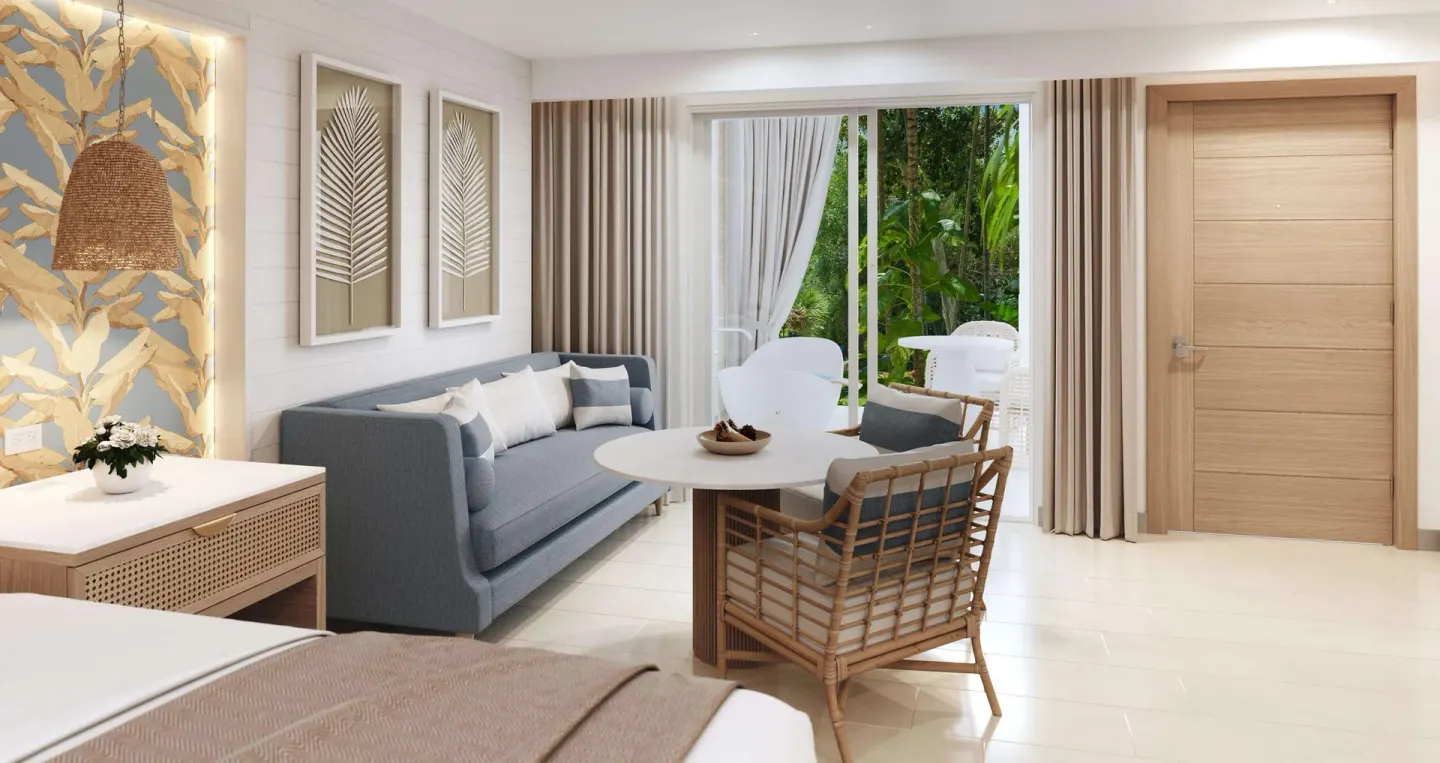 Guest room sitting area with sofa, round table, and sliding doors at Sandals Montego Bay.
