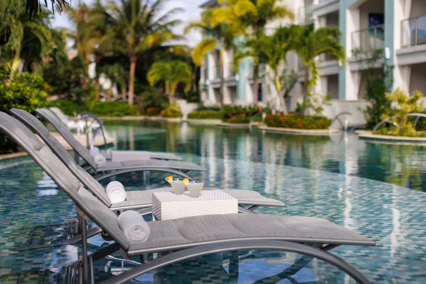 In-water loungers with drinks beside a lagoon pool at Sandals Montego Bay.