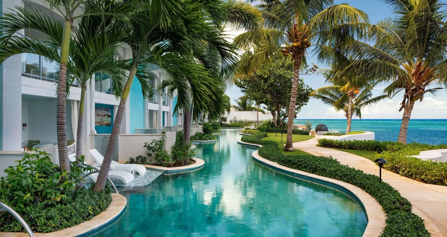 Palm-lined lagoon pool beside oceanfront rooms at Sandals Montego Bay.