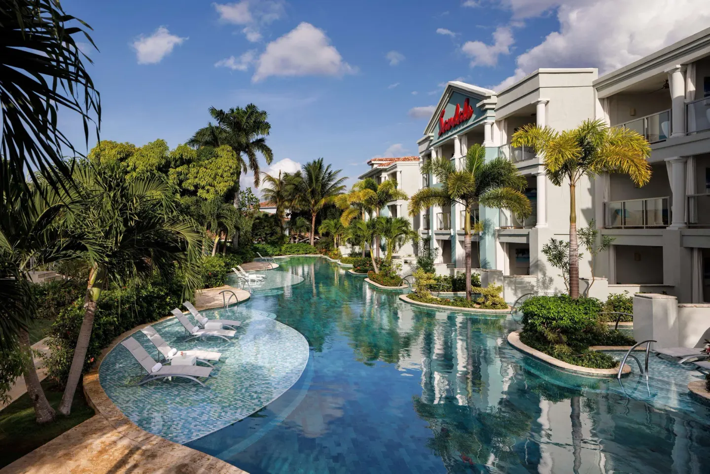 Lagoon-style pool beside guest buildings and palms at Sandals Montego Bay.