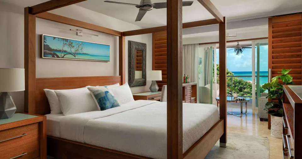 Four-poster king bedroom with balcony ocean view at Sandals Montego Bay.