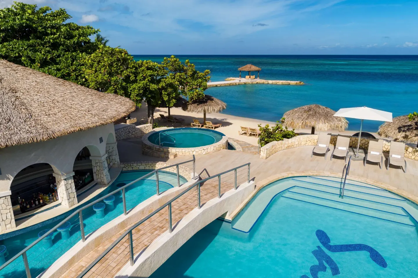 Oceanfront pool terrace with swim-up bar and beach views at Sandals Montego Bay.