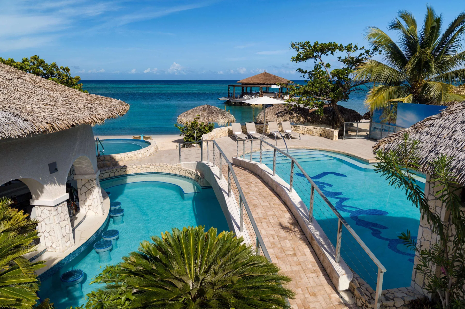 Oceanfront pool terraces with thatched roofs at Sandals Montego Bay.