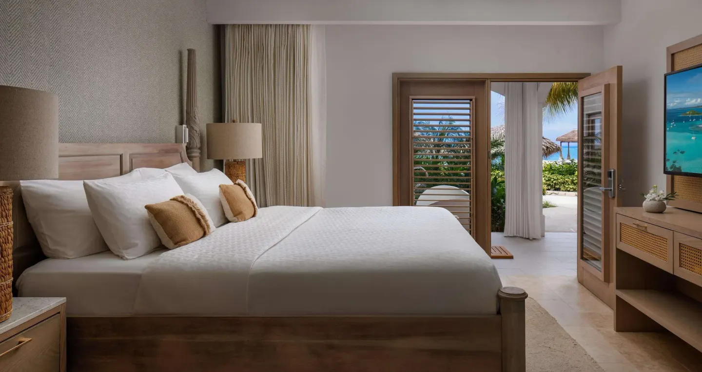King bedroom with open patio doors and partial sea view at Sandals Montego Bay.