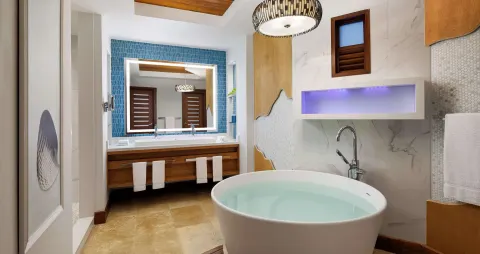 Bathroom with round soaking tub and blue tile vanity wall at Sandals Montego Bay.